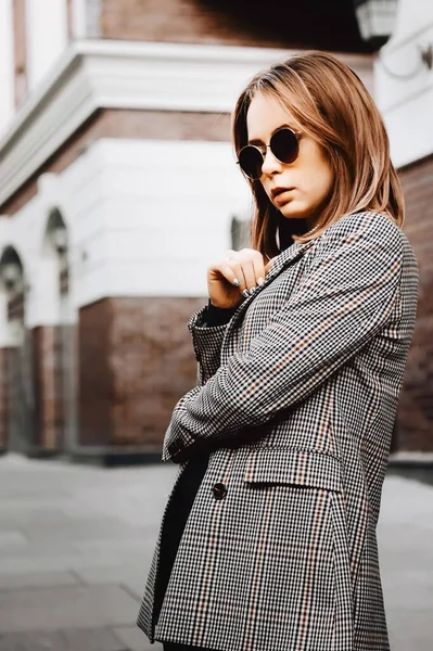 A girl in a business suit in the old town with glasses