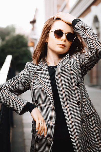 A girl in a business suit in the old town with glasses