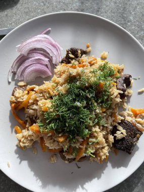 Pilaf, bir tabak et, pirinç, baharatlı havuç, kurutulmuş meyve ve badem ve kimyon, tarçın ve zerdeçal kokulu. Gri arka planda gri bir plaka üzerinde. Estern mutfağı. Yüksek kalite fotoğraf