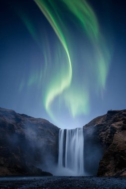 Güzel bir Auora Borealis namı diğer Kuzey Işıkları İzlanda 'daki Skogafoss şelalesinin üzerinde.