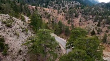 Güzel bir dağın ve dağ yolunun üzerinde uçan bir dron görüntüsü. Dağların üzerinden bulutlu havada uçan, hindideki dağlık arazi.
