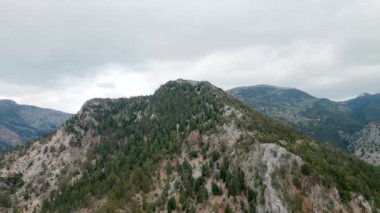 Dağ zirvesinin tepesinden kuş bakışı görüş. Dağların üzerinden bulutlu havada uçan, hindideki dağlık arazi.