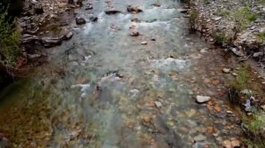 Bir dağ nehrinin mavi suyu yukarıdan uçan bir dron tarafından filme alınır.