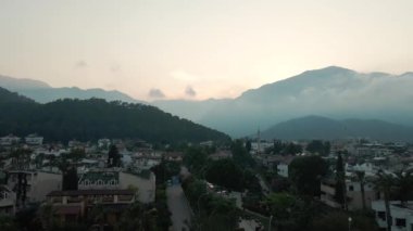 Hindi dağlarında gün batımı, vadide deniz kenarında bir şehir.