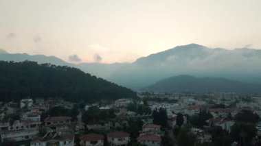 Hindi dağlarında gün batımı, vadide deniz kenarında bir şehir.