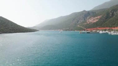 Körfezdeki sahil şehrinin havadan görünüşü, Akdeniz dağları arasında tatil köyü ve liman manzarası kurulması.