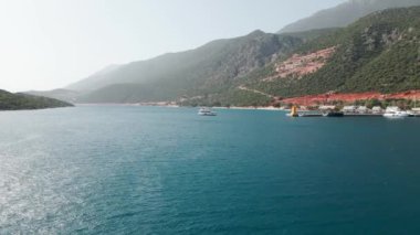 Körfezdeki sahil şehrinin havadan görünüşü, Akdeniz dağları arasında tatil köyü ve liman manzarası kurulması.