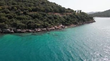 Türkiye 'nin Antalya ilinin Kas kentinde Akdeniz' in güzel turkuaz sularıyla muhteşem bir göl ve küçük bir plaj. Güneşli bir günde Kas Körfezi 'nde küçük bir yat. Steadicam görüntüleri gösteriliyor