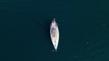 Yukarıdan bakıldığında, turkuazda yüzen beyaz bir yelkenlinin çarpıcı hava manzarası, berrak su. Türkiye, Kas