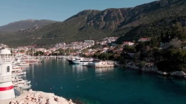 Kas 'ın güneşli marinası manzarası, sahilde oteller, dağlar, bir sürü beyaz yat, botlar, ufuk çizgisi. Türk güneşli manzarası