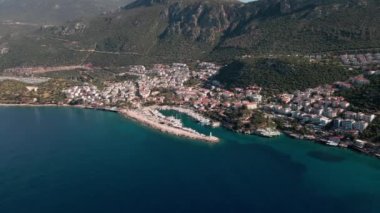 Kas 'ın güneşli marinası manzarası, sahilde oteller, dağlar, bir sürü beyaz yat, botlar, ufuk çizgisi. Türk güneşli manzarası