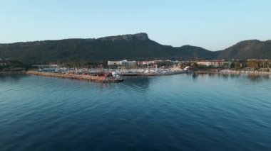 İHA, Türkiye 'nin güneyindeki deniz kıyısında şehirden uzaklaşıyor. Şafak, iskele, plaj görünür, insan yok.