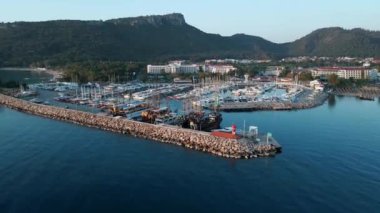 Deniz, liman, tekne ve şehir mimarisinin hava aracı görüntüsü. Türkiye 'nin Kemer tatil beldesinin görkemli manzarası. 4k İHA 'dan panoramik gün doğumu görünümü