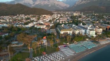 Türkiye 'nin Kemer kentindeki bir plajın havadan çekilmiş videosu. İHA 'larla, tatil köyü üzerinde gün doğumu görüntüleri. Şemsiyeler ve güneşlikler kumsalda sıralanır