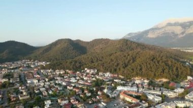 Bir yaz günü güneş beyaz villaların ve tepelerin üzerinden doğarken, insansız bir hava aracı Kemer kıyı şehrinin üzerinden uçuyor..