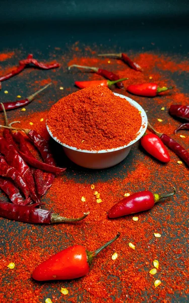 Red chili pepperand chili powder on a dark background.