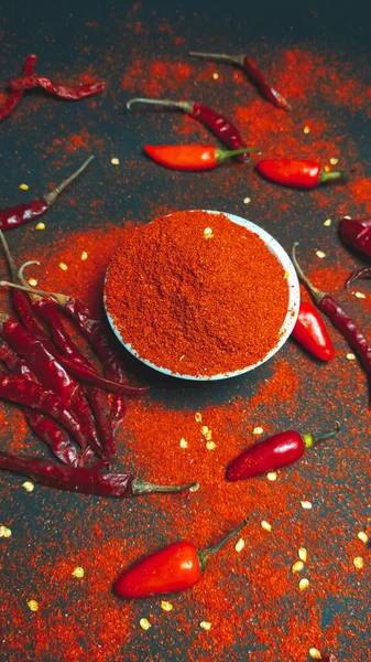 Red chili pepperand chili powder on a dark background.