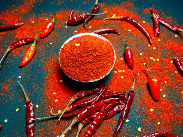 Red chili pepperand chili powder on a dark background.