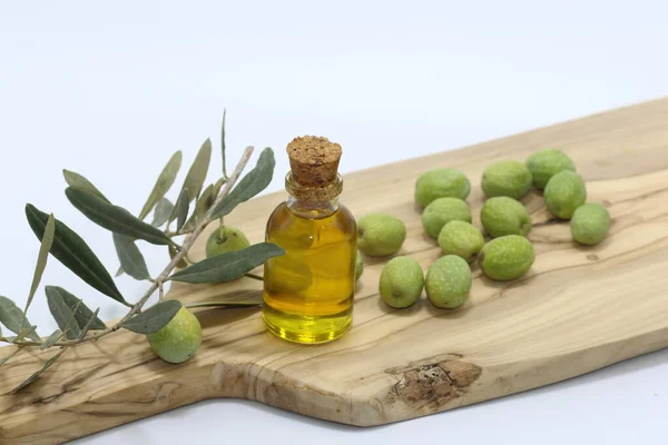 olive oil in a bottle and green olives on wood