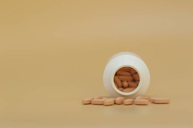 Sarı arka planda beyaz hapların döküldüğü ilaç şişesini kapat. Eczane konsepti.