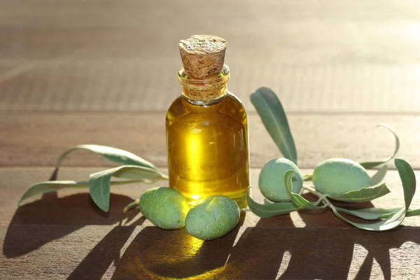 olive oil in a bottle and green olives on wooden table