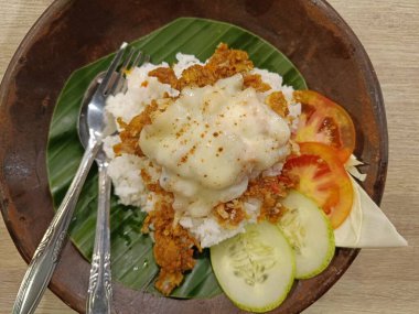 Eritilmiş mozzarella peynirli kızarmış tavuk pilavı ahşap tabakta servis edilir.