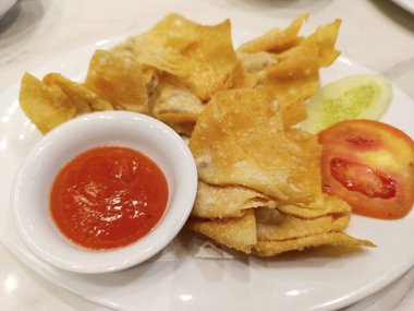 Beyaz tabakta sıcak kırmızı soslu kızarmış Wonton yemeği, Çin mutfağı yemekleri..