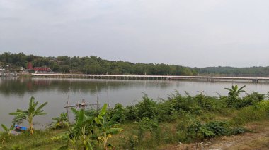 Üzerinde uzun beyaz bir köprü bulunan gölün güzel manzarası..