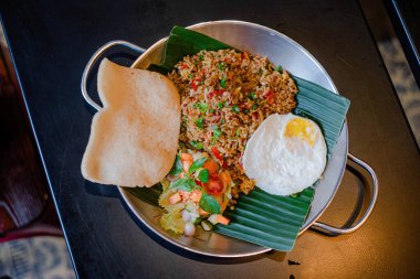 Nasi goreng babat ya da baharatlı kızarmış pirinç alüminyum tavada ve muz ağacı yapraklarında servis edilir.