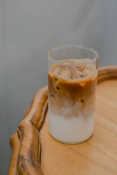 A glass of coffee latte in the corner of a wooden table