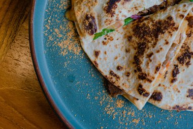 Bir tabak Quesadilla, yanında sebze, soğan ve biraz patates cipsi.