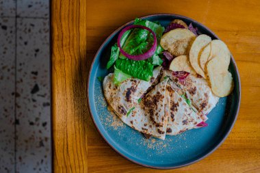 Bir tabak Quesadilla, sebze, soğan ve biraz patates gevreğiyle çok yakından çekilmiş ve detaylandırılmış.