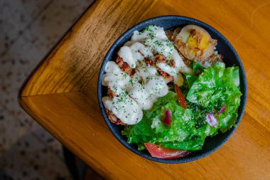 Tavuklu pilav, mayonez, sebze ve kaynamış yumurta ile ahşap masa ve arka plan bulanık.