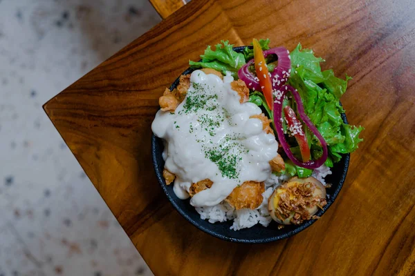 Tavuklu pilav, mayonez, sebze ve kaynamış yumurta ile ahşap masa ve arka plan bulanık.