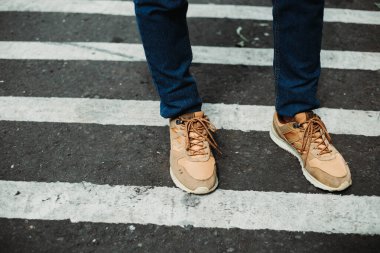 Zebra caddesinde duran spor ayakkabı ve lacivert kot giyen bir adam kıyafeti.