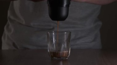 Bir adam masanın üzerinde taşınabilir manuel espresso makinesi kullanarak kahve yapıyor.
