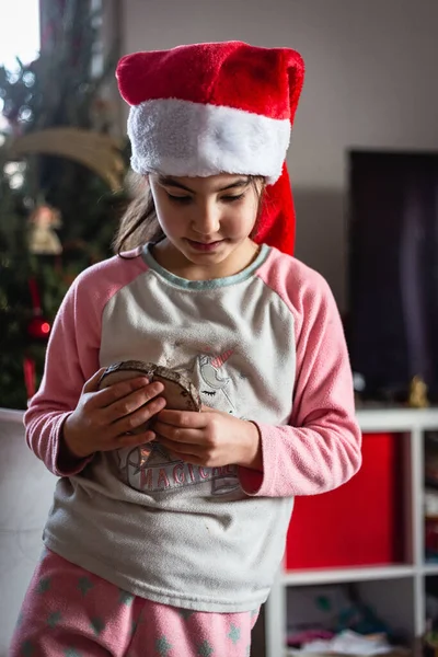 Κορίτσι Φορώντας Καπέλο Santa Και Πιτζάμες Παρακολουθεί Χριστουγεννιάτικη Διακόσμηση Πήρε — Φωτογραφία Αρχείου