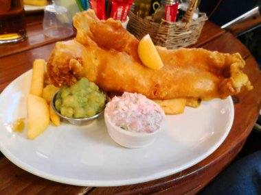 İngiltere 'de lapa bezelye ve sos ile izole edilmiş balık ve patates kızartması.