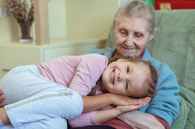 Yaşlı bir kadın ve küçük bir kızın portresi, büyükannesi torununa sarılıyor, aile bağları, yaşlılık ve gençlik, 90 yaşında, yaşlı bir yüzdeki kırışıklıklar, güzel bir yaşlılık, bir kadın ve bir çocuk.