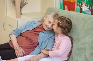 Yaşlı bir kadın ve küçük bir kızın portresi, büyükannesi torununa sarılıyor, aile bağları, yaşlılık ve gençlik, 90 yaşında, yaşlı bir yüzdeki kırışıklıklar, güzel bir yaşlılık, bir kadın ve bir çocuk.