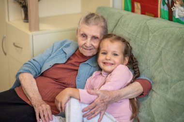 Yaşlı bir kadın ve küçük bir kızın portresi, büyükannesi torununa sarılıyor, aile bağları, yaşlılık ve gençlik, 90 yaşında, yaşlı bir yüzdeki kırışıklıklar, güzel bir yaşlılık, bir kadın ve bir çocuk.