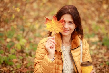 Güzel genç bir kadın ormanda bir patika boyunca yürür, sonbahar kuru yaprakları yere dökülür, yaprak düşer, Kasım.