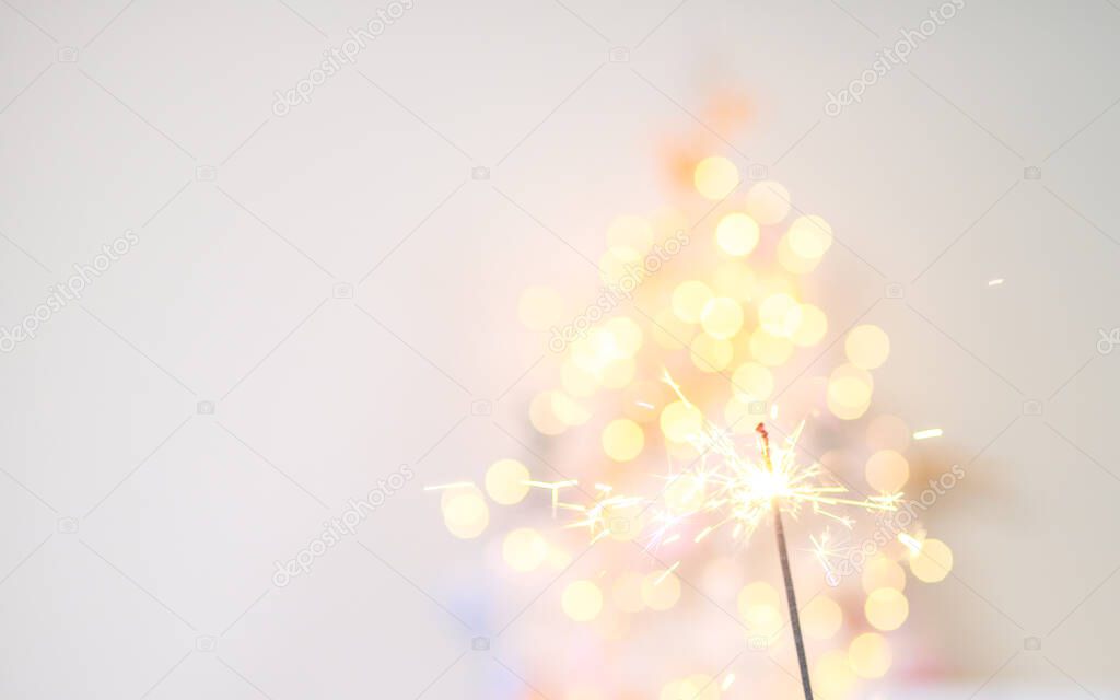 Beautiful sparkles from sparklers on the background of New Year's bokeh, Christmas mood, glitter, festive background.
