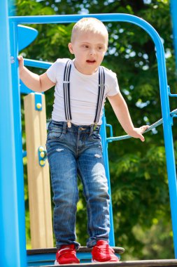 Down sendromlu bir çocuk oyun parkında oynuyor. Çocuğun gelişiminde gecikme var..