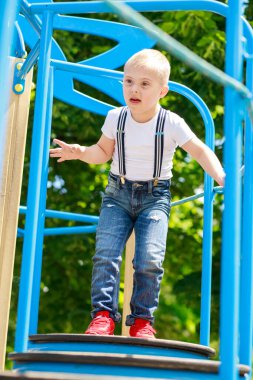 Down sendromlu bir çocuk oyun parkında oynuyor. Çocuğun gelişiminde gecikme var..