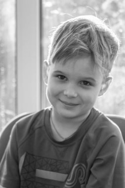 Sevimli bir çocuğun siyah beyaz portresi, çocuk gülümsüyor, çocuğun yüzünde neşe.