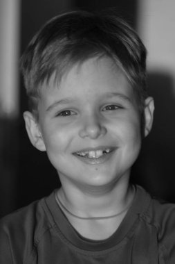 Sevimli bir çocuğun siyah beyaz portresi, çocuk gülümsüyor, çocuğun yüzünde neşe.