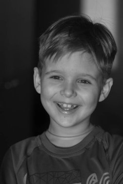 Sevimli bir çocuğun siyah beyaz portresi, çocuk gülümsüyor, çocuğun yüzünde neşe.