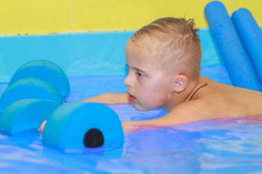 Down sendromlu bir çocuk havuzda yüzmeyi öğrenir..