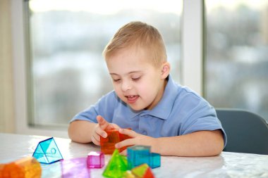 Down sendromlu bir çocuk geometrik figürlerle oynar, plastik bir yapıcı, tip 21 trisonomi, ekstra bir kromozom..